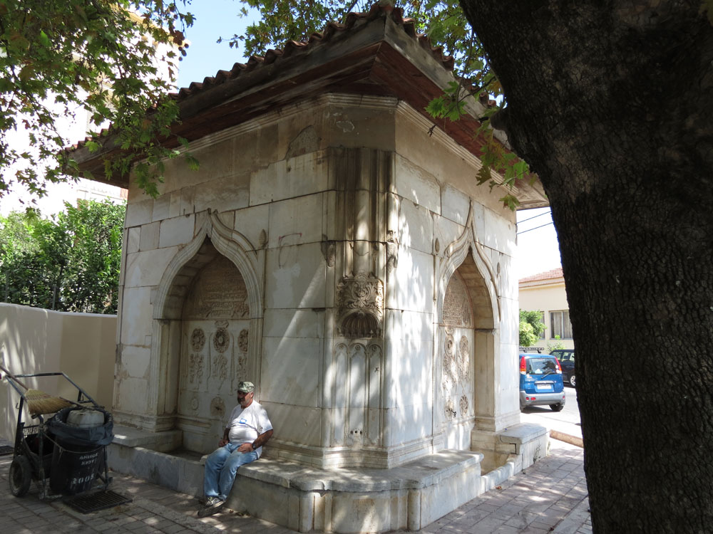Osmanlı eseri çeşme ve gölgesinde dinlenen temizlik işçisi